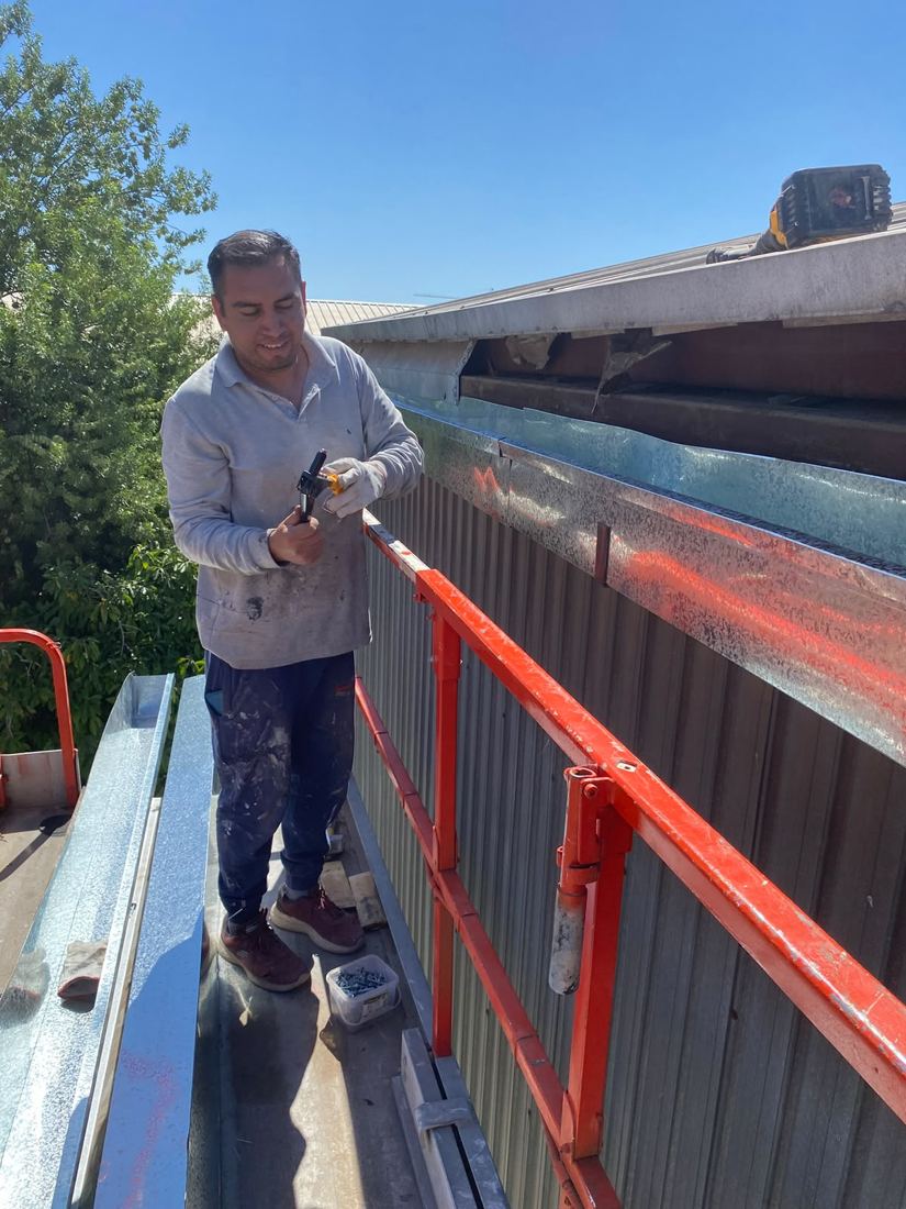 Maestro instalando canaleta galvanizada desde plataforma elevadora